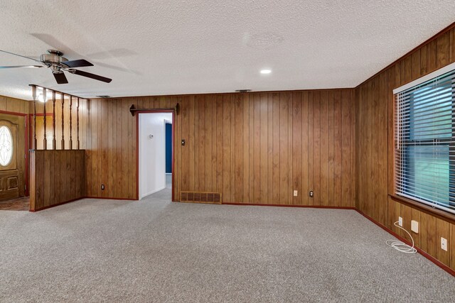 carpeted spare room with a wealth of natural light, visible vents, ceiling fan, and a textured ceiling