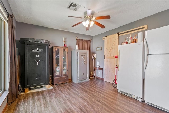 interior space featuring wood finished floors, visible vents, freestanding refrigerator, and a barn door
