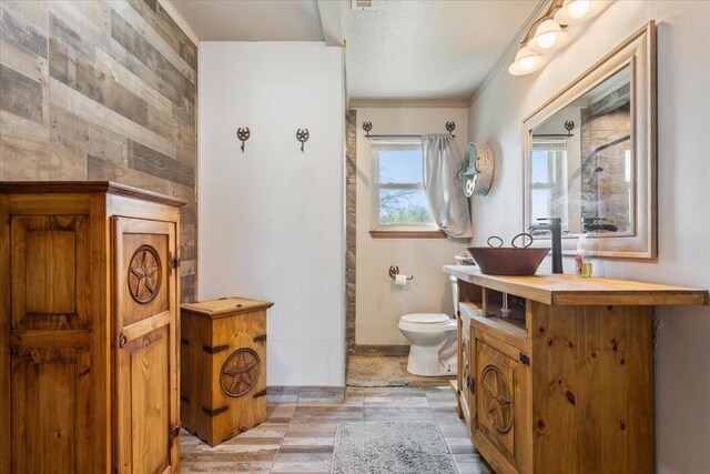 bathroom with baseboards, toilet, crown molding, and vanity