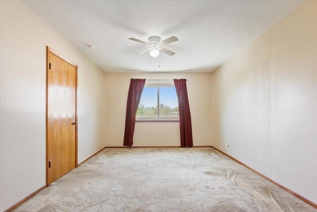 unfurnished room with ceiling fan, baseboards, and light carpet