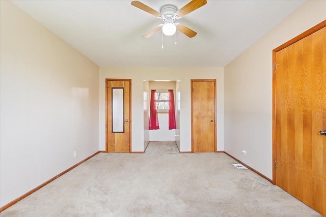 unfurnished bedroom with a ceiling fan, light carpet, and baseboards