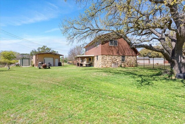 view of yard featuring fence, a garage, and an outbuilding