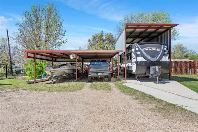 view of parking featuring dirt driveway, fence, and a detached carport