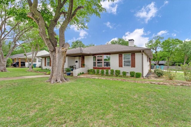 single story home with a chimney, a front yard, and brick siding