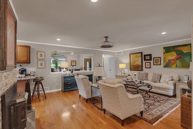 living area featuring light wood-style flooring, visible vents, and ornamental molding