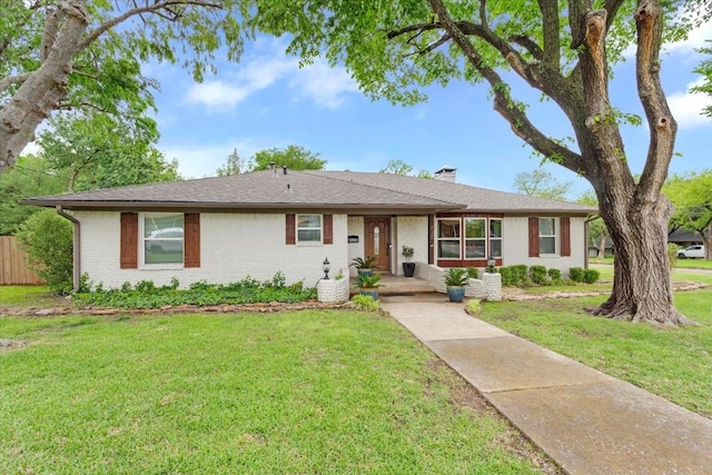 ranch-style house featuring a chimney, brick siding, and a front lawn