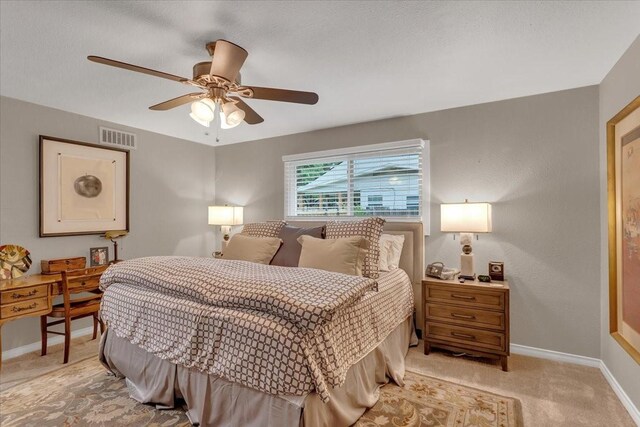 bedroom with baseboards, visible vents, a ceiling fan, and light colored carpet