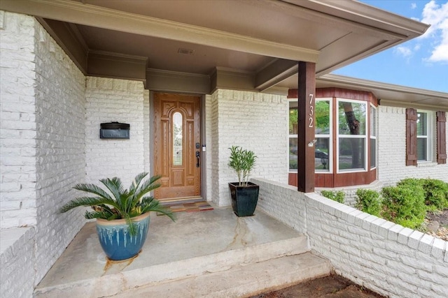 property entrance featuring a porch and brick siding