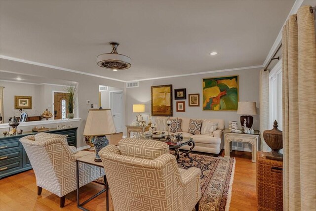 living room featuring crown molding, recessed lighting, visible vents, and light wood-style flooring
