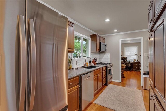 kitchen with a sink, stainless steel appliances, recessed lighting, light wood finished floors, and backsplash