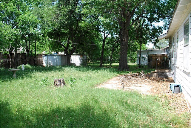 view of yard featuring fence, an outdoor structure, and a shed