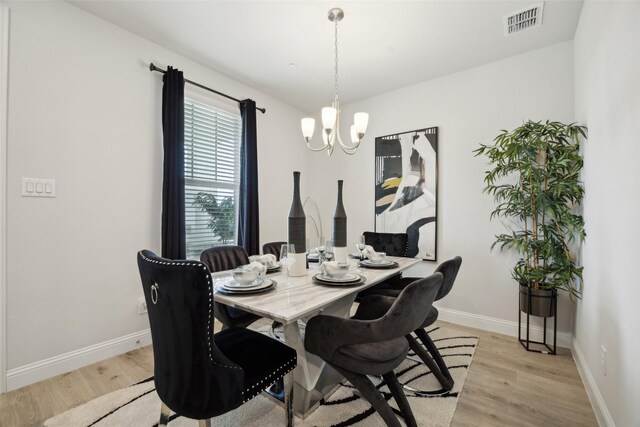dining space with visible vents, an inviting chandelier, baseboards, and light wood-type flooring