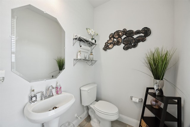 half bathroom featuring baseboards, toilet, and a sink