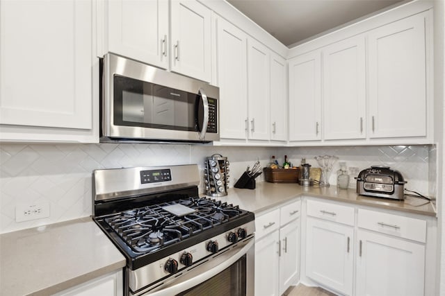 kitchen featuring white cabinetry, tasteful backsplash, stainless steel appliances, and light countertops