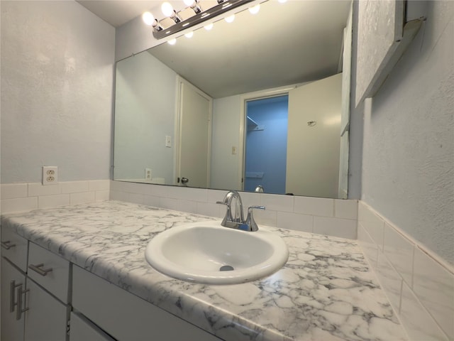 bathroom featuring a textured wall and vanity