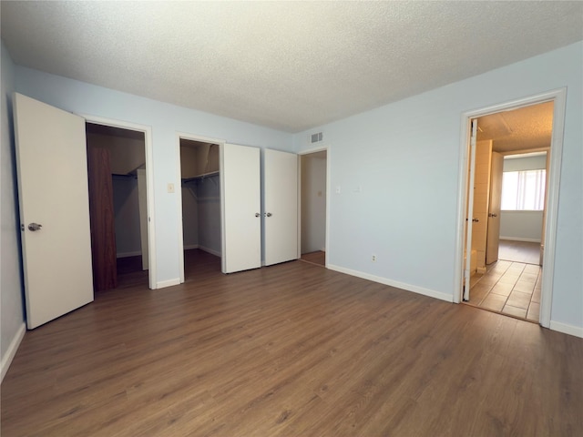 145 Trellis Pl, Richardson, TX 75081 - unfurnished bedroom featuring wood finished floors, baseboards, a textured ceiling, and a spacious closet