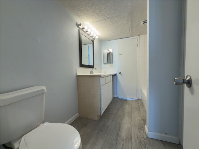 bathroom with vanity, toilet, visible vents, baseboards, and wood finished floors