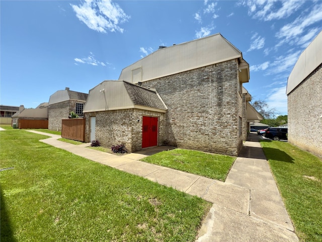 exterior space featuring a lawn and brick siding