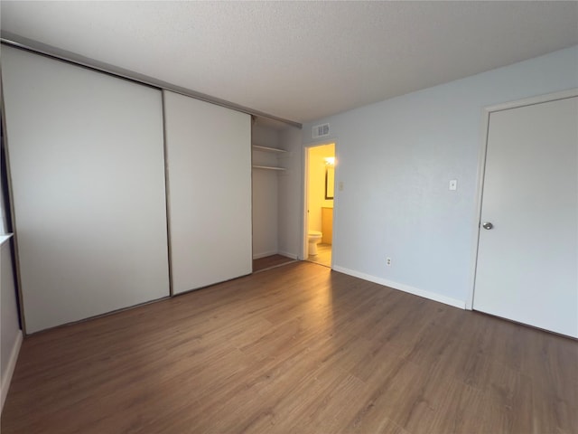 unfurnished bedroom with baseboards, visible vents, light wood-style floors, and a closet