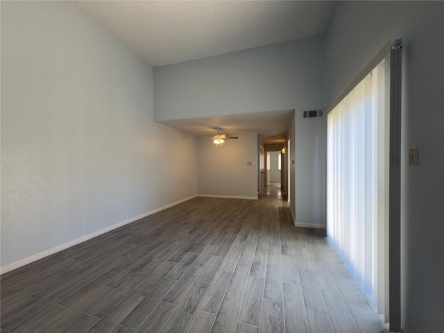 empty room featuring dark wood-style flooring, visible vents, ceiling fan, and baseboards