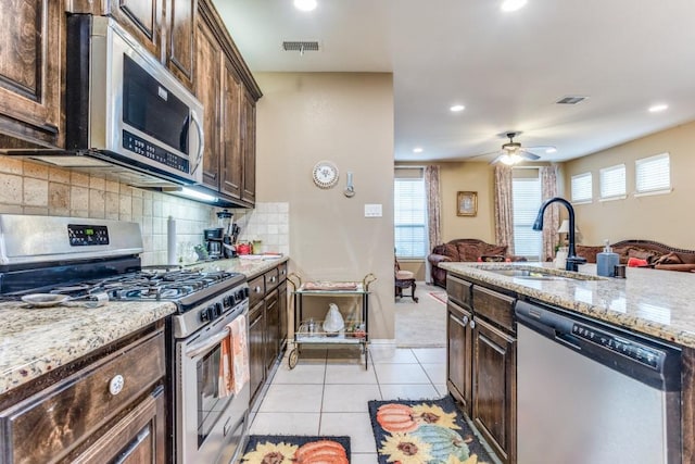 kitchen with visible vents, stainless steel appliances, open floor plan, and a sink