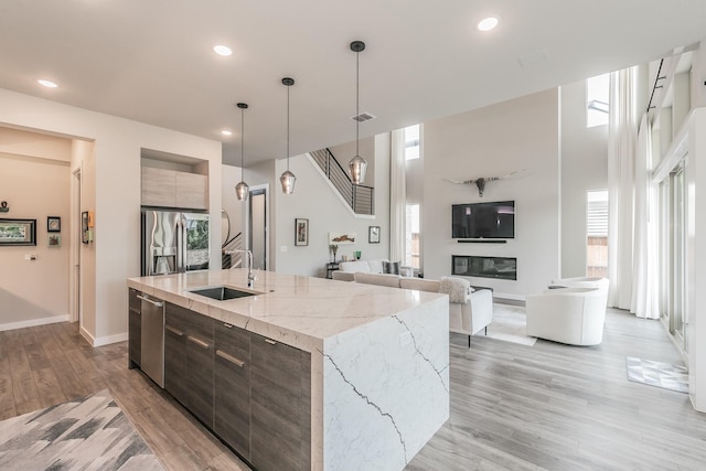 3901 Campania Ct, Colleyville, TX 76034 - kitchen with a kitchen island with sink, stainless steel appliances, light wood finished floors, a sink, and modern cabinets