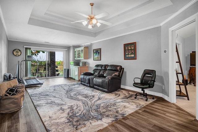 living room featuring crown molding, a raised ceiling, ceiling fan, and wood finished floors