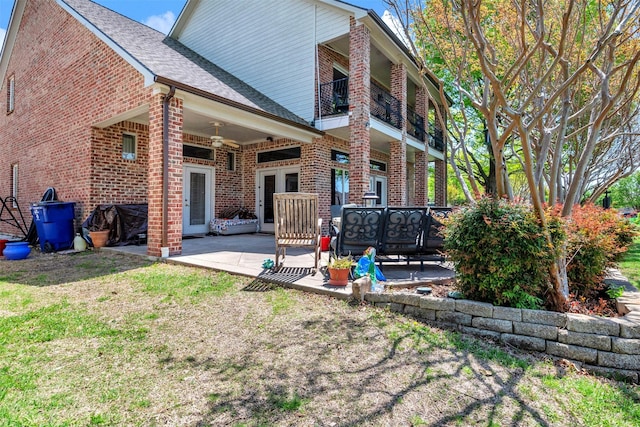 rear view of property featuring a patio, brick siding, ceiling fan, and a balcony