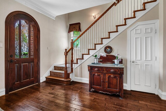 foyer entrance featuring stairs, arched walkways, baseboards, and dark wood-style floors