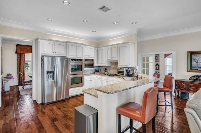 1701-1703 Weiskopf Dr, Heath, TX 75032 - kitchen featuring appliances with stainless steel finishes, a sink, a peninsula, light stone counters, and crown molding