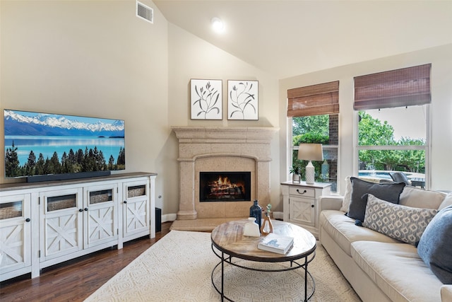 living room with dark wood-style floors, a premium fireplace, high vaulted ceiling, visible vents, and baseboards