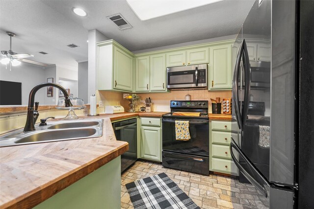 kitchen featuring black appliances, butcher block countertops, green cabinets, and a sink