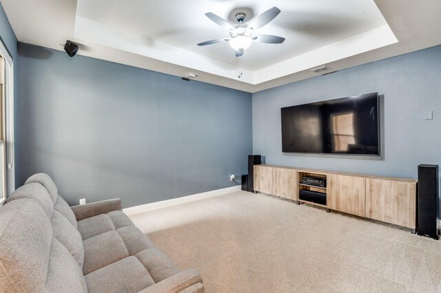 carpeted living room featuring ceiling fan, baseboards, a raised ceiling, and visible vents