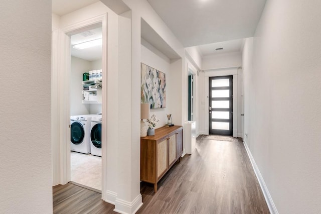 entryway with wood finished floors, washing machine and clothes dryer, and baseboards