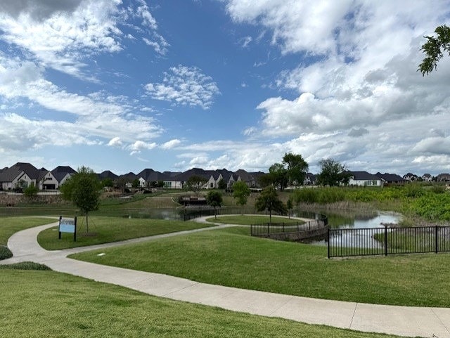 view of property's community with a residential view, a lawn, and a water view