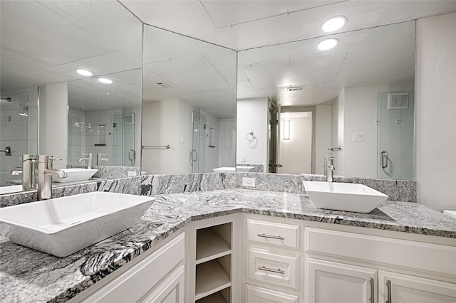 full bathroom featuring recessed lighting, a stall shower, double vanity, and a sink