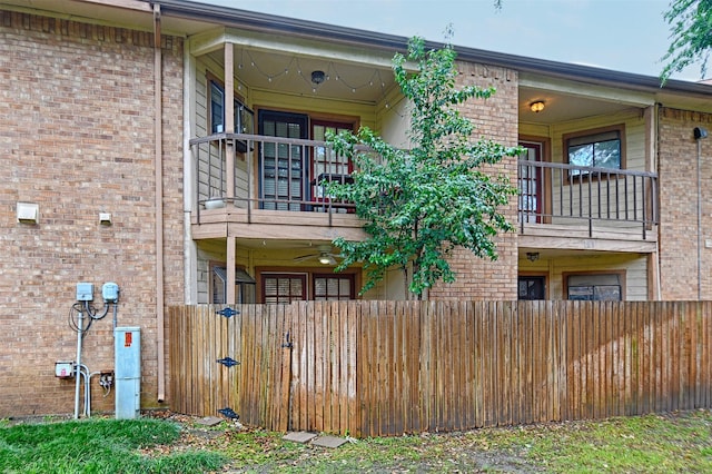 back of house with brick siding, fence private yard, and a balcony