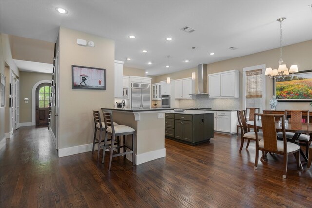 5313 Ridgedale Ave, Dallas, TX 75206 - kitchen with appliances with stainless steel finishes, wall chimney exhaust hood, a kitchen bar, a chandelier, and a peninsula