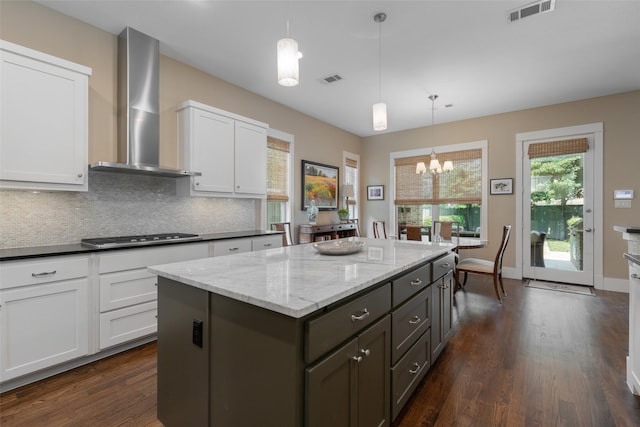 5313 Ridgedale Ave, Dallas, TX 75206 - kitchen with wall chimney exhaust hood, stainless steel gas cooktop, dark wood-style floors, a kitchen island, and white cabinets