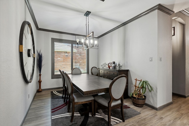 dining area with crown molding, baseboards, an inviting chandelier, and light wood finished floors