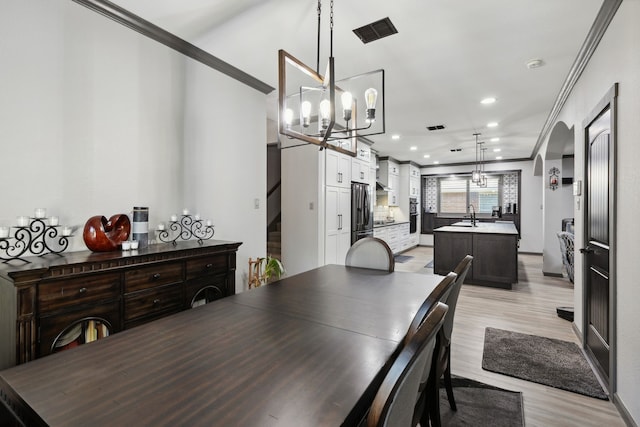dining room featuring crown molding, a chandelier, and light wood-style floors