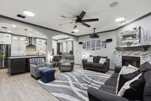 living area with crown molding, a ceiling fan, and visible vents