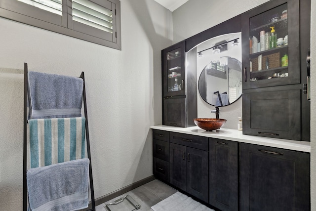 bathroom with baseboards, a textured wall, tile patterned floors, and vanity