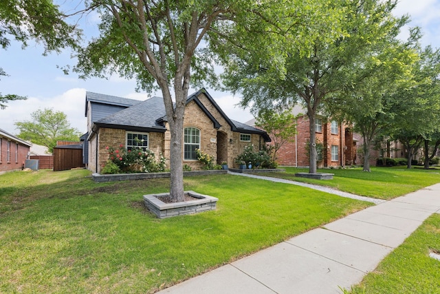 view of front of house featuring a shingled roof, a front yard, and brick siding
