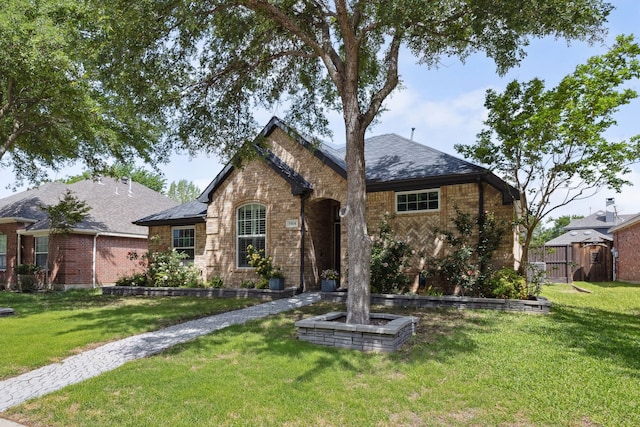 view of front of property with fence, a shingled roof, a front yard, and brick siding