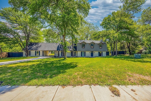view of front of house featuring a front lawn, driveway, an attached carport, and fence