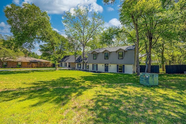 rear view of house with brick siding, fence, and a yard