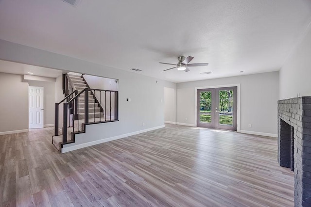 unfurnished living room featuring wood finished floors, stairway, baseboards, visible vents, and a ceiling fan
