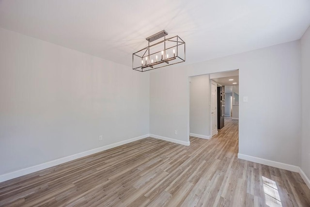 unfurnished dining area featuring a notable chandelier, baseboards, and light wood-type flooring