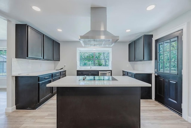 kitchen featuring island range hood, light wood finished floors, light countertops, and black electric stovetop
